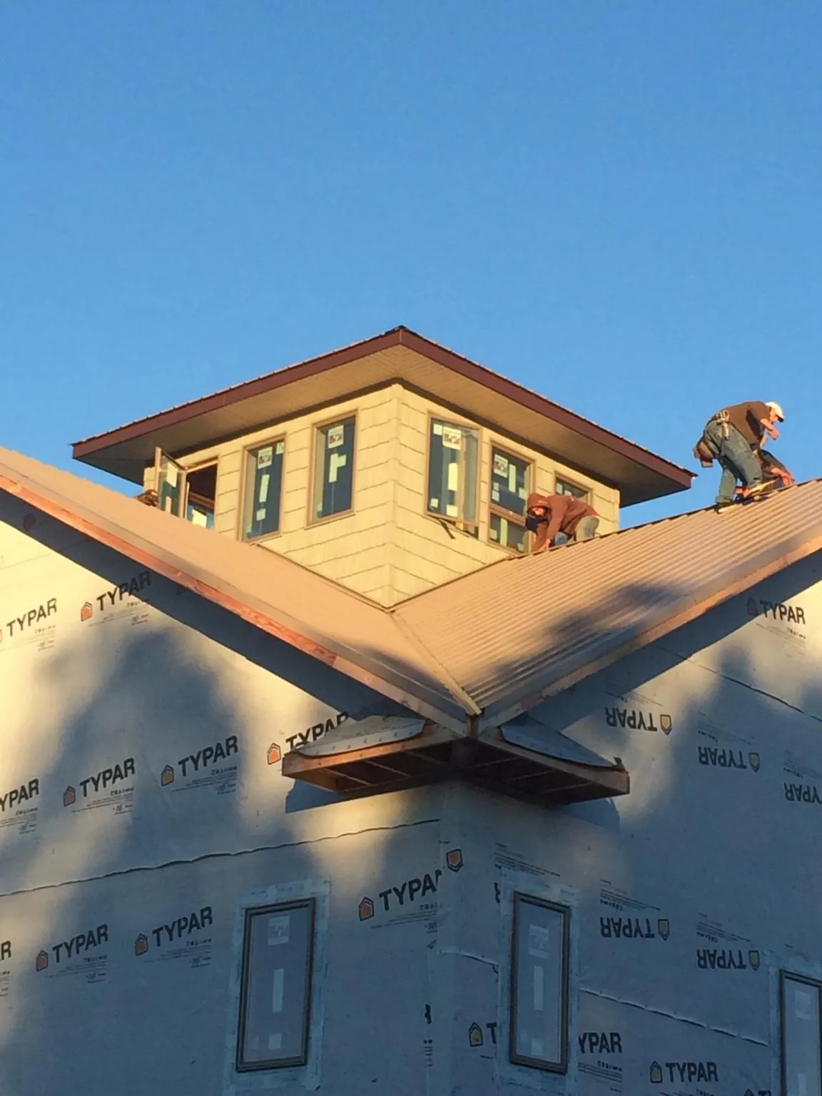 Roofers working around a rooftop cupola on a new metal roof at sunset — Roof Waterproofing in Pearl River by Roofing Brothers